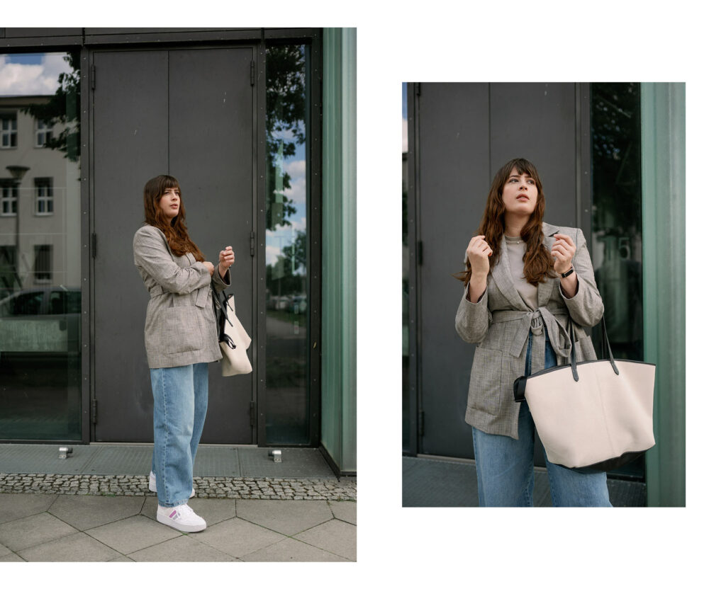 Andrea trägt eine weite Jeans mit grauem Oversize-Blazer, weißen Sneakern und cremefarbener Tote Bag – perfekter Casual-Business-Style für den Alltag.