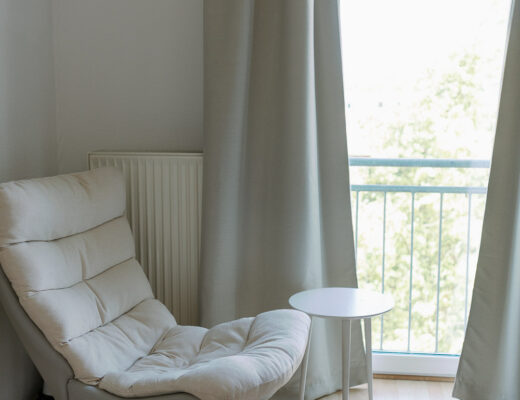 Wohnzimmer mit gemütlichem Sessel und Gardine als Lichtschutz für besseren Babyschlaf