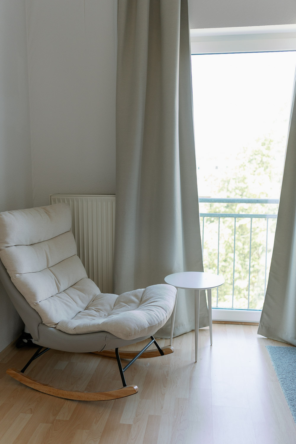 Wohnzimmer mit gemütlichem Sessel und Gardine als Lichtschutz für besseren Babyschlaf