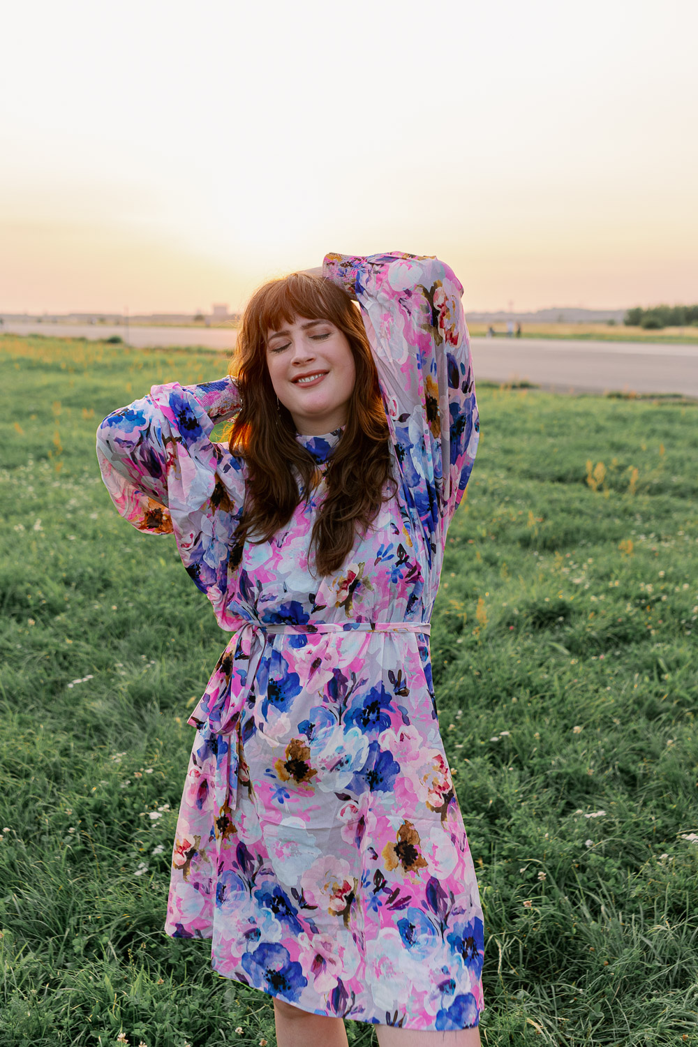 Andrea von andysparkles im bunten Kleid mit langen Ärmeln beim Sonnenuntergang auf dem Tempelhofer Feld in Berlin.