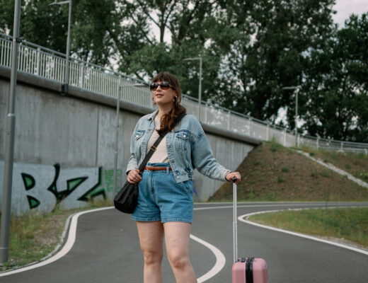 Andrea von andysparkles mit kleinem pinken Koffer und Jeansjacke – Beispiel für Reiseoutfits und Packtipps, wie viele Kleidungsstücke für 7 Tage unterwegs passen