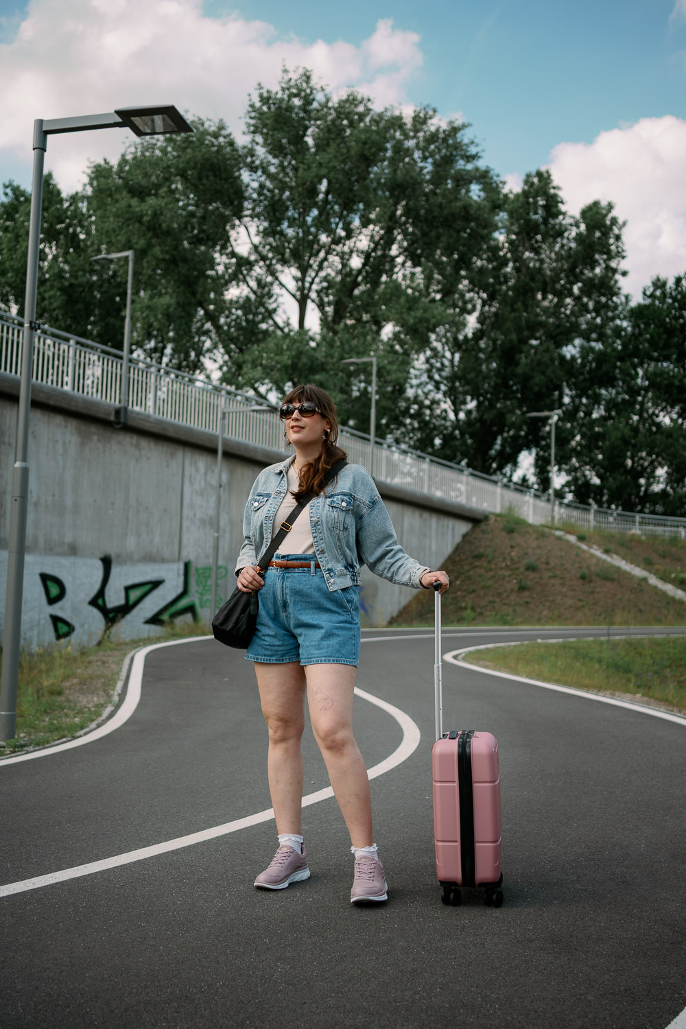 Andrea von andysparkles mit kleinem pinken Koffer und Jeansjacke – Beispiel für Reiseoutfits und Packtipps, wie viele Kleidungsstücke für 7 Tage unterwegs passen
