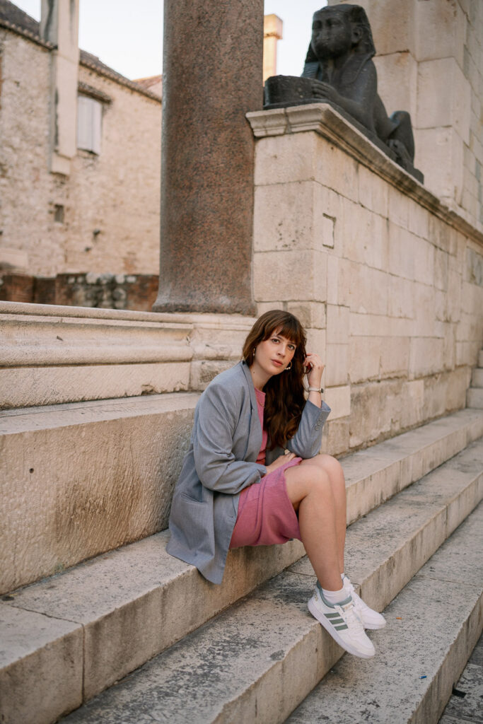 Andrea von andysparkles im pinken Kleid und grauem Blazer in der Altstadt von Split