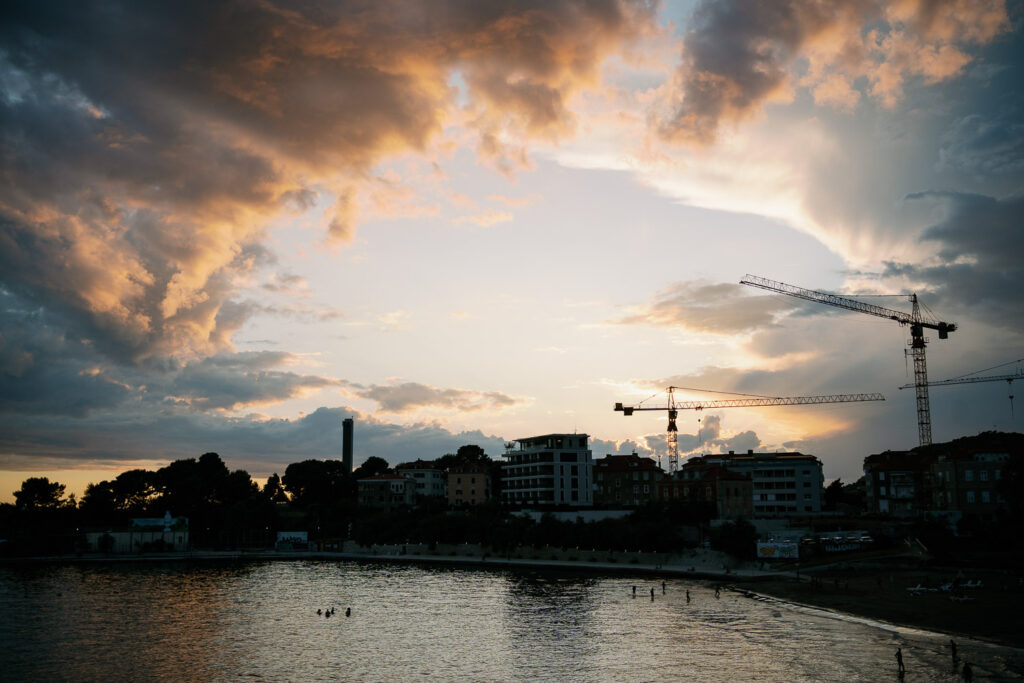 Sonnenuntergang über Strand von Split mit Kränen und Wolkenhimmel