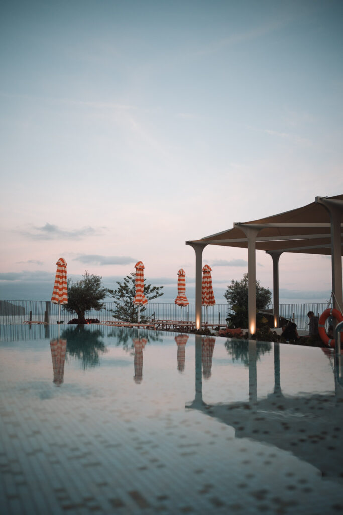 Infinity Pool mit orangen Sonnenschirmen bei Sonnenuntergang in Madeira