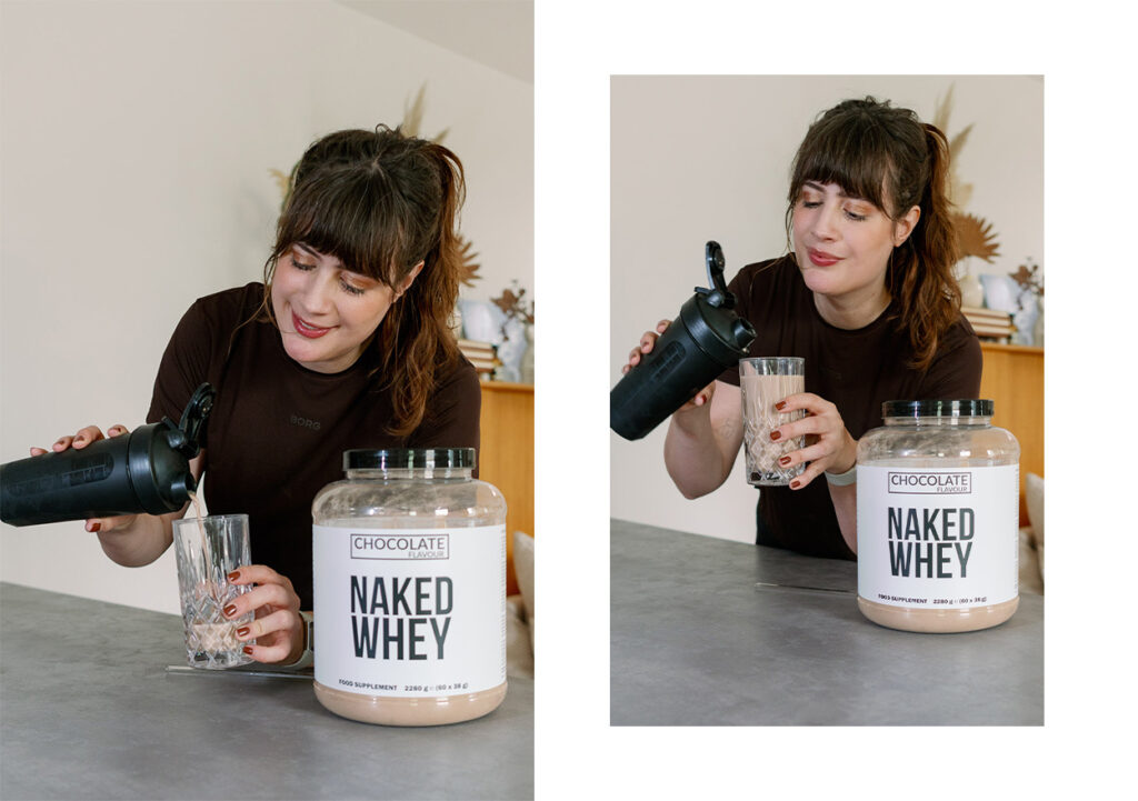 Andrea gießt sich einen Schoko-Proteinshake aus dem Shaker ins Glas, das Grass-Fed Whey Protein von Naked Nutrition steht auf dem Tisch.