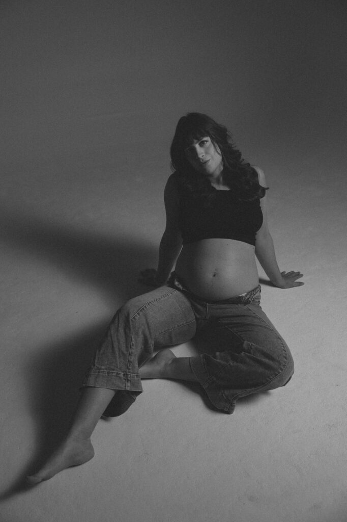 Andrea Funk im Studio, sitzend mit Babybauch, nachdenklicher Moment während der Schwangerschaft – mentale Vorbereitung auf die Geburt