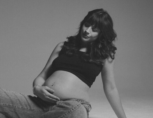 Andrea Funk hält ihren Babybauch und lächelt sanft – mentale Vorbereitung auf die Geburt und bewusste Verbindung zum Baby