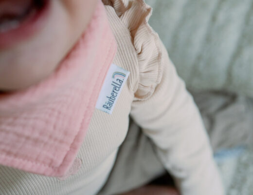 Baby mit ersten Zähnchen und rosa Halstuch – Zähne putzen beim Baby