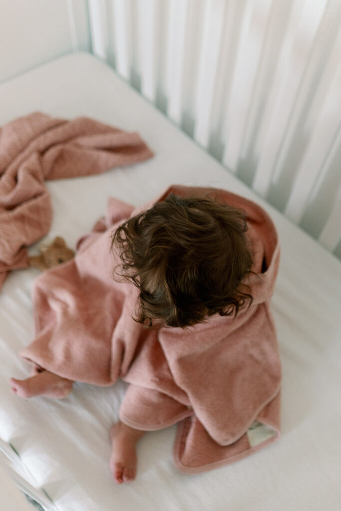 Baby in rosa Handtuch eingekuschelt im Bett nach dem Baden