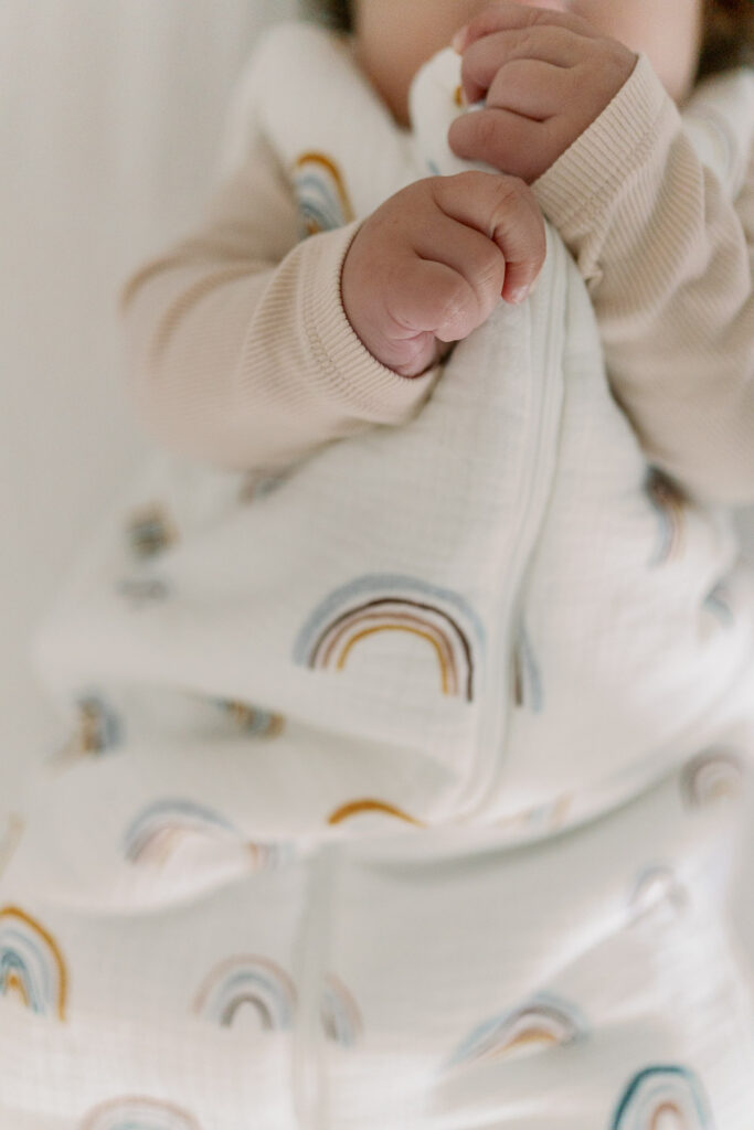 Babyhände halten Schlafsack mit Regenbogenmuster in der Abendroutine mit Zähneputzen