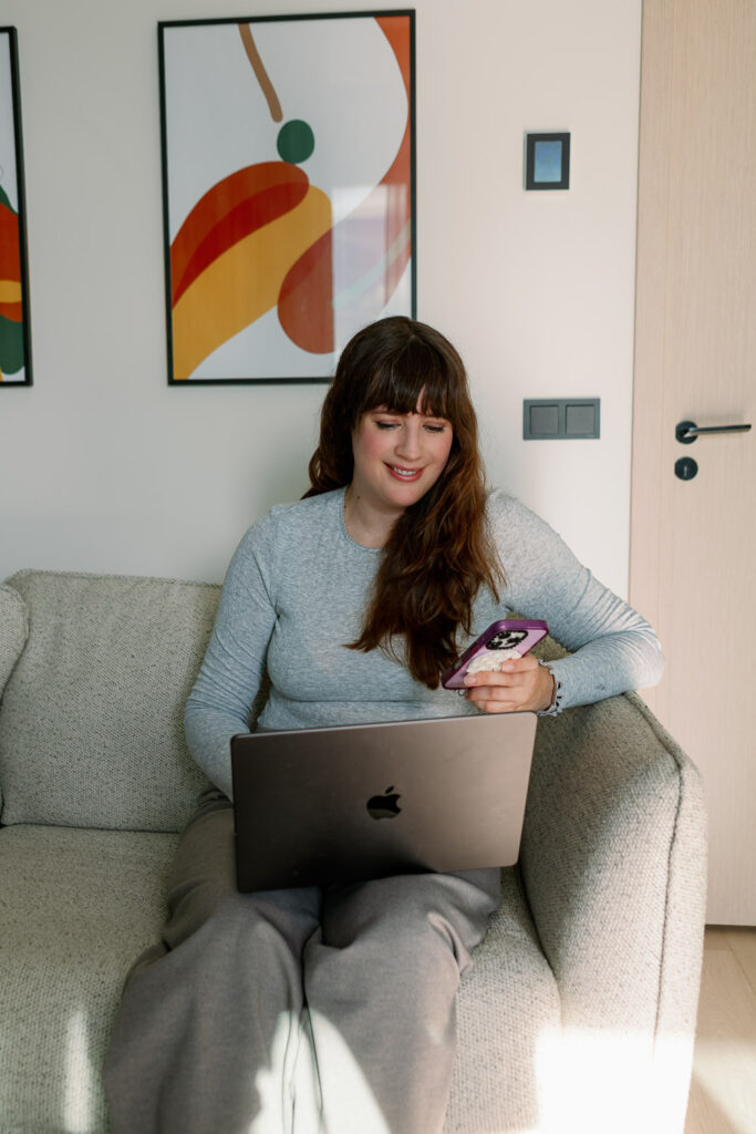 Mama sitzt mit Laptop und Smartphone auf dem Sofa und plant neue Blogartikel