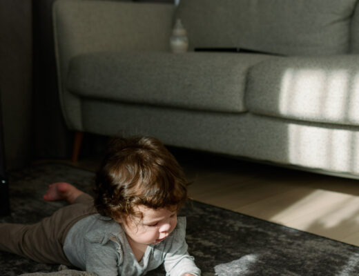Geschenkideen für Kinder im Alltag: Baby spielt auf dem Teppich mit seinem Lieblingsspielzeug