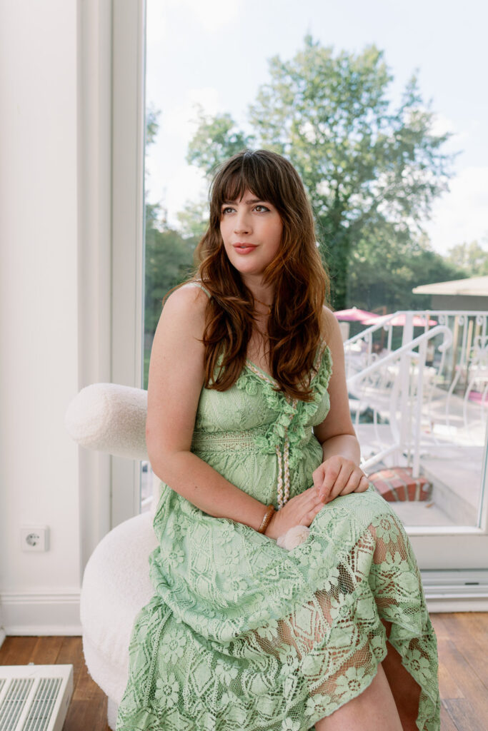 Andrea von andysparkles sitzt im grünen Spitzenkleid am Fenster und blickt nach draußen, Haarausfall bei Frauen