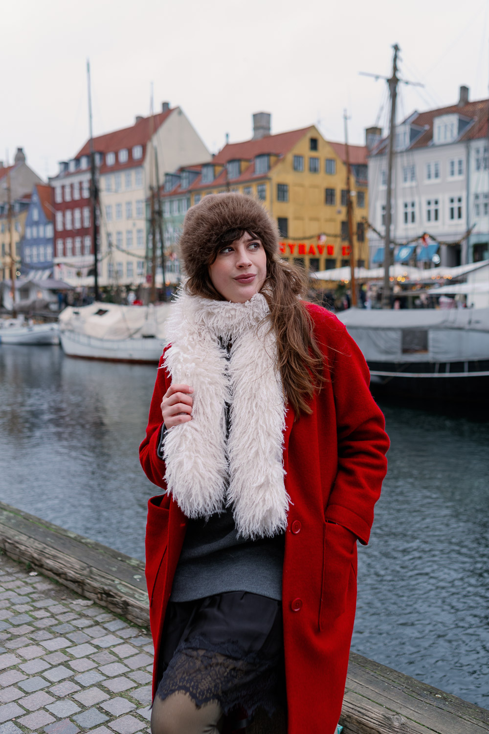 Andrea von andysparkles in rotem Mantel, Fake-Fur-Hut und flauschigem Schal am Hafen in Kopenhagen, Virale Winter Fashion Hacks für warmes Sightseeing