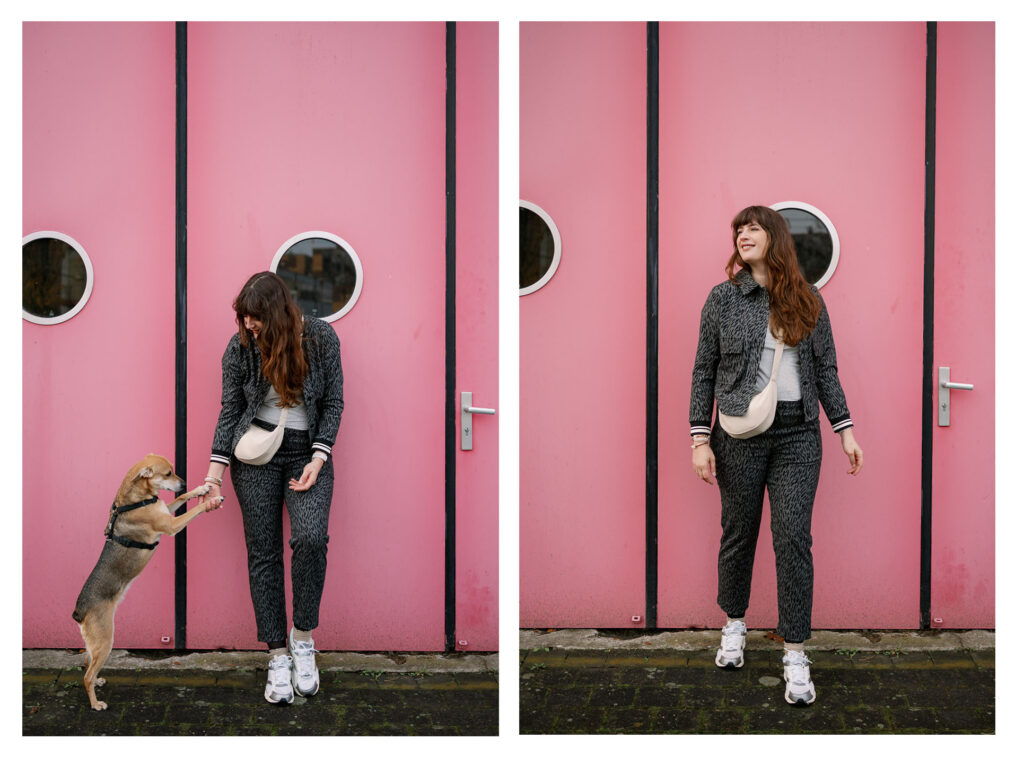 Andrea von andysparkles mit Hund vor pinker Tür, grauer gemusterter Zweiteiler, Sneaker und helle Crossbody Bag