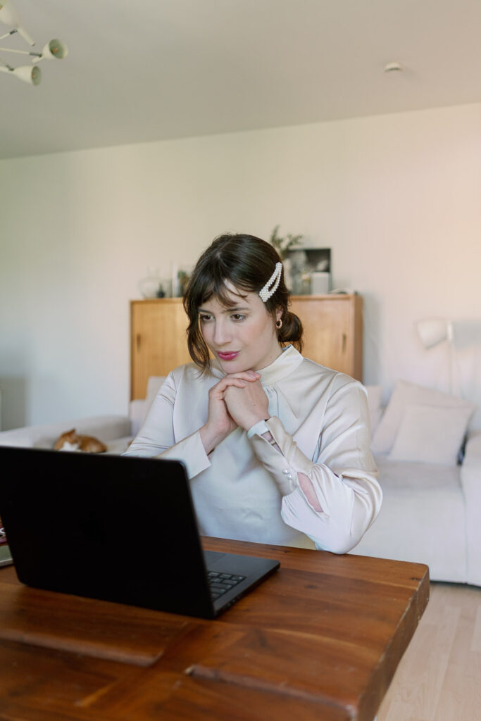 Andrea from andysparkles in the home office with a light blouse on the laptop for a casual office look