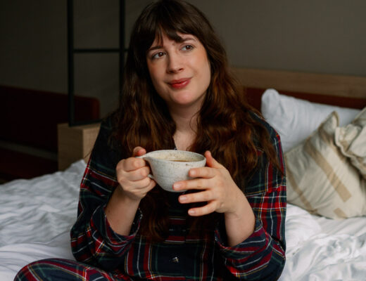 Andrea von andysparkles im karierten Pyjama mit einer Tasse Kaffee im Bett – Tipps gegen Schlafmangel als Mama.