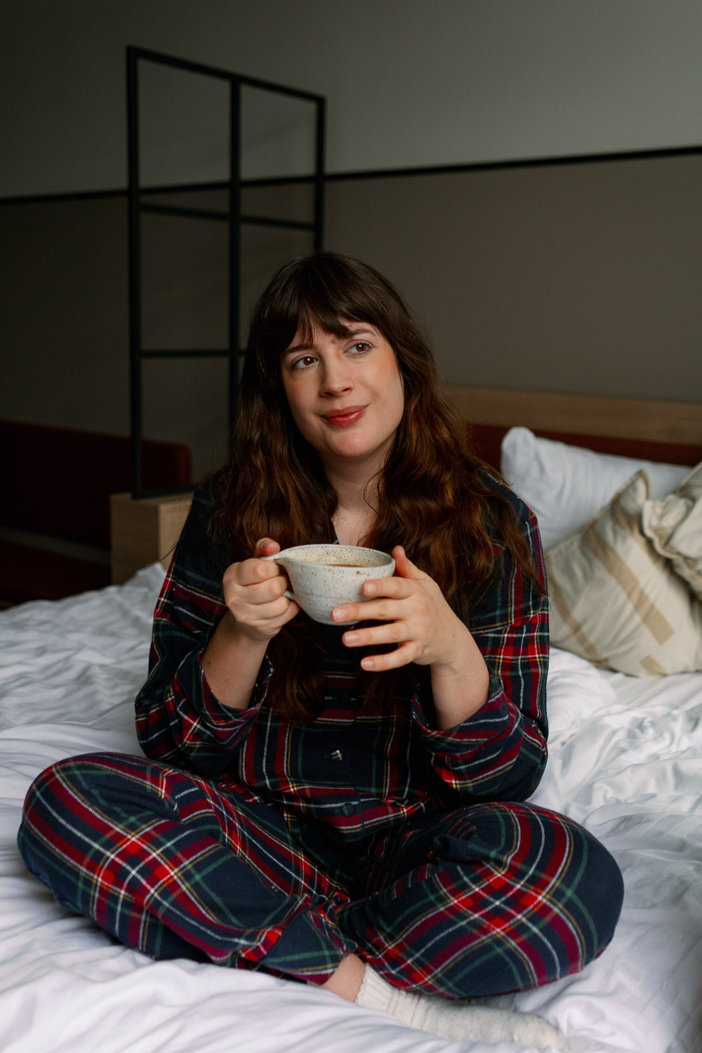 Andrea von andysparkles im karierten Pyjama mit einer Tasse Kaffee im Bett – Tipps gegen Schlafmangel als Mama.