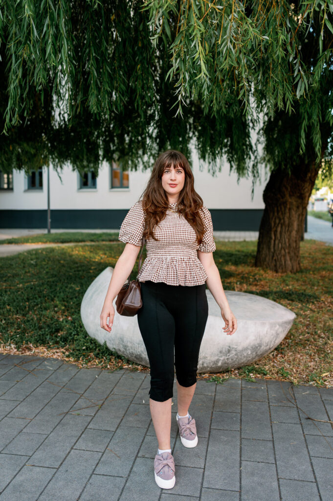 Andrea von andysparkles mit brauner Umhängetasche, schwarzer Hose und Sneakers in Berlin