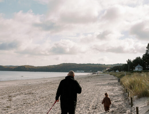Mann an der Ostsee mit Hund und Kleinkind während er sich die Frage stellt, wie man einen guten Optiker findet