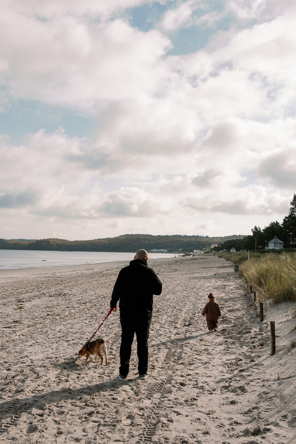 Mann an der Ostsee mit Hund und Kleinkind während er sich die Frage stellt, wie man einen guten Optiker findet